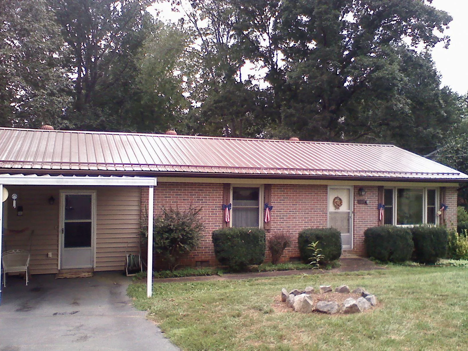 Bronze metal roof and carport on a brick ranch home — Roof Repair work by our crew in Seville